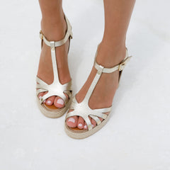 Metallic gold T-strap wedge sandals made from premium Italian leather, worn by a woman on a white background. Available at Australian designer shoe stores across Victoria